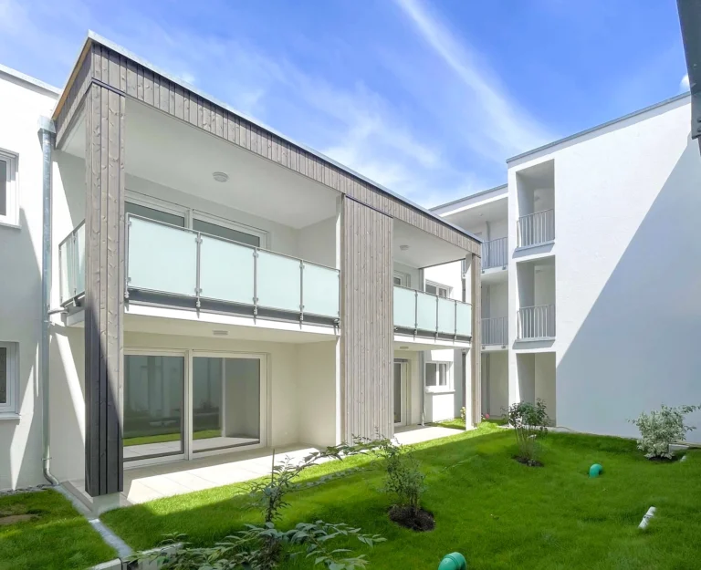 Neubauwohnungen mit überdachten Balkonen und gepflegtem Innenhof.