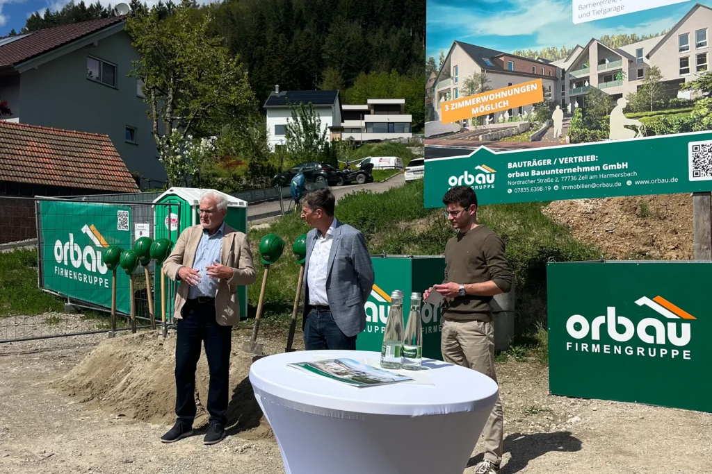 Projektvorstellung Mehrgenerationenwohnen Fischerbach mit Beteiligten vor großem Bauschild der orbau Firmengruppe