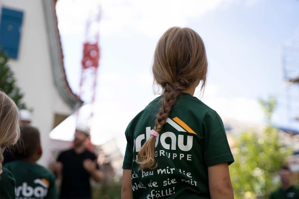 Kind im orbau T-Shirt blickt bei der Baustellenbesichtigung in Biberach zu einem Baukran