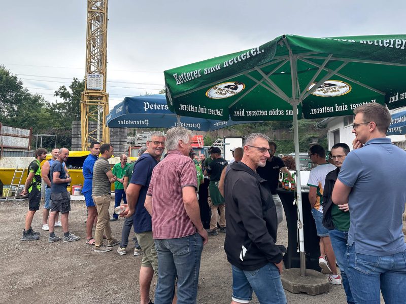 Kollegen beim Sommerfest der orbau Gruppe unter Sonnenschirmen im Gespräch, Gengenbach Bauhof 2025.