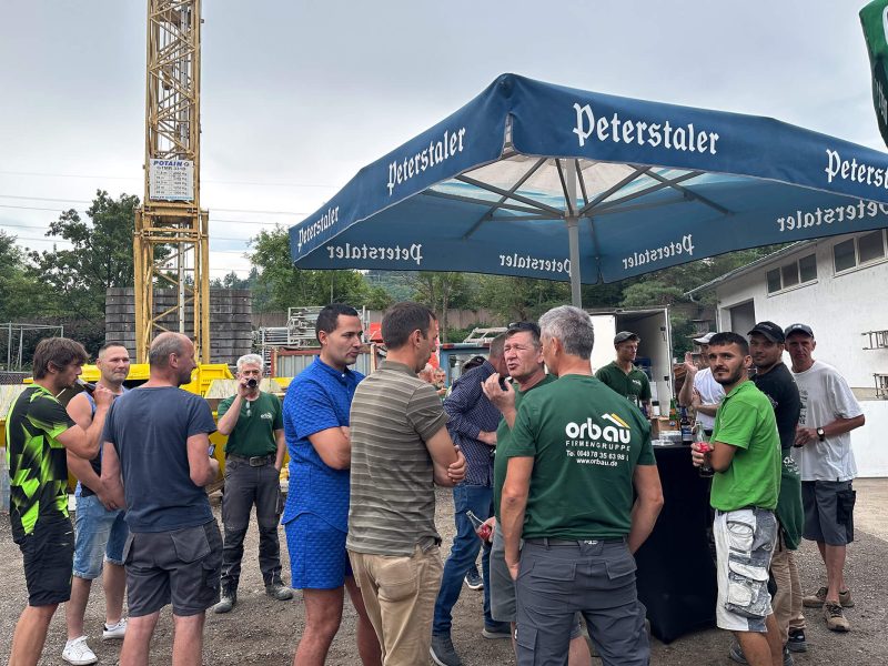 Mitarbeitende der orbau Firmengruppe im Gespräch auf dem Bauhof beim Sommerfest 2025.