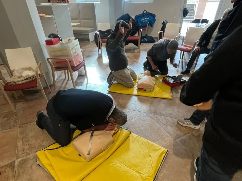 Gewerbliche Mitarbeiter von orbau üben die Herz-Lungen-Wiederbelebung an Übungspuppen.