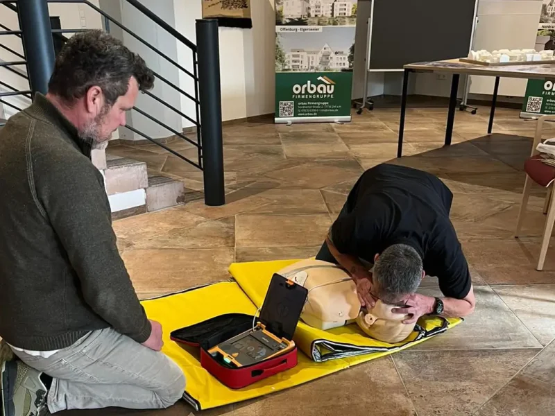 Teilnehmer übt den Einsatz eines Defibrillators an einer Reanimationspuppe.