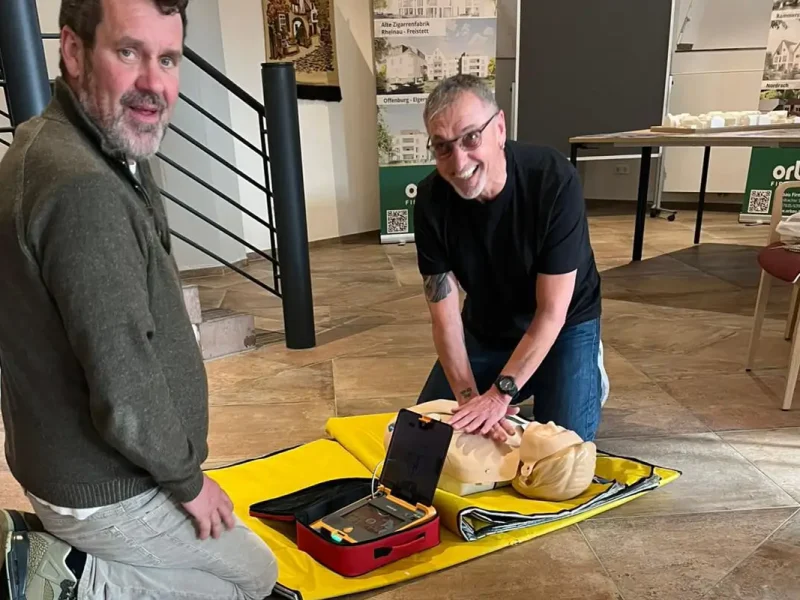 Ersthelfer-Übung mit Wiederbelebungsmaßnahmen und Defibrillator.