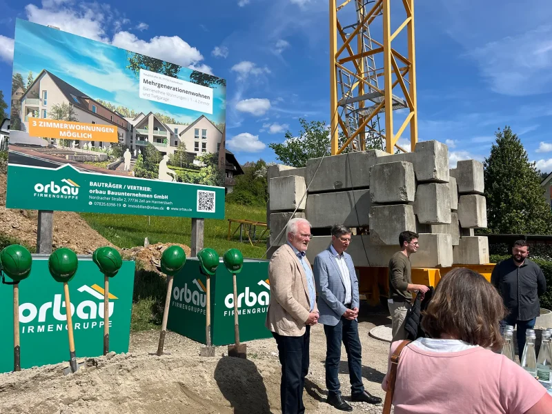 Spatenstich in Fischerbach mit Kran, Spaten und Projektbanner der orbau Firmengruppe auf der Baustelle