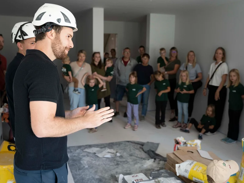 Mitarbeiter erklärt Kindern bei der orbau Baustellenbesichtigung in Biberach die Arbeiten auf der Baustelle.