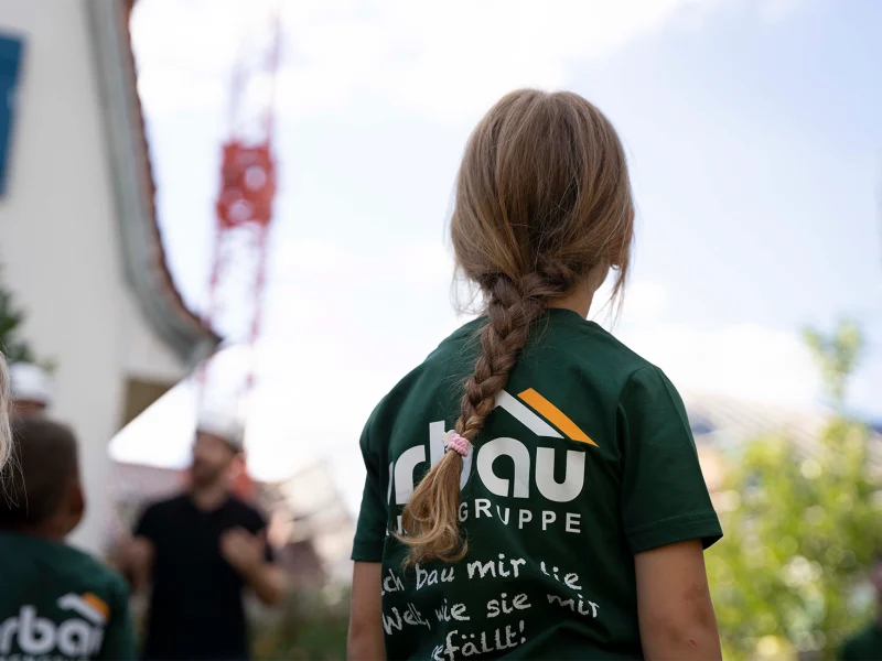 Kind im orbau T-Shirt blickt bei der Baustellenbesichtigung in Biberach zu einem Baukran