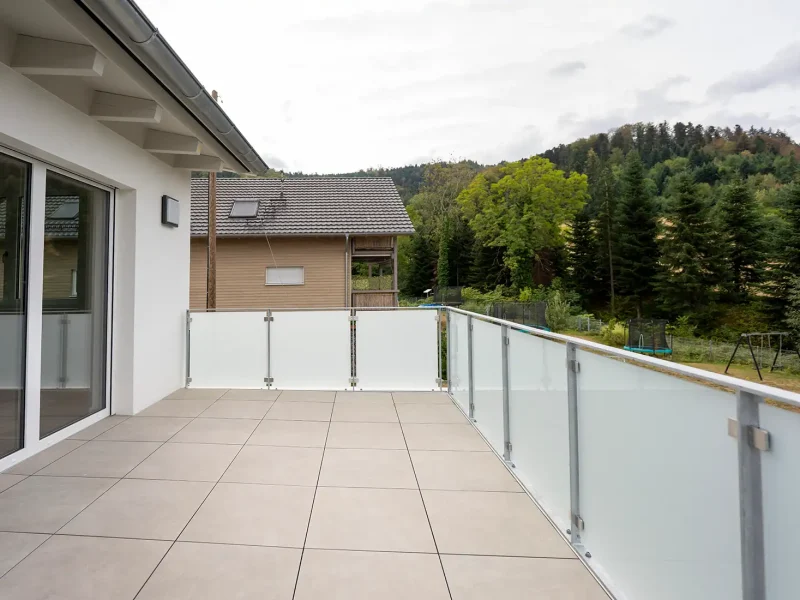 Großzügige Dachterrasse mit Glasgeländer und Blick ins Grüne am sanierten Wohnhaus