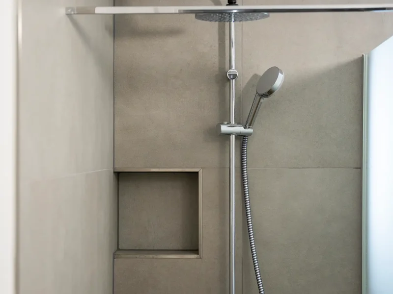 Moderne bodengleiche Dusche mit Glasabtrennung und eingelassener Wandablage