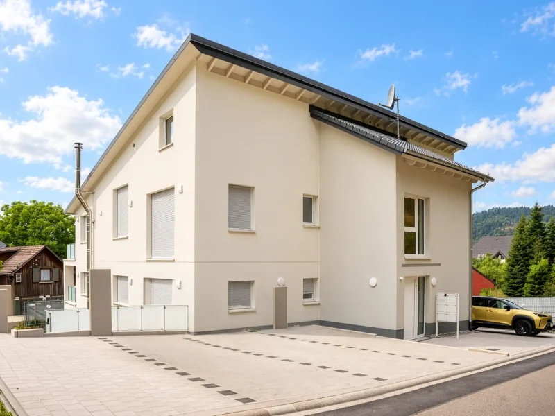 Straßenansicht des sanierten Wohnhauses mit Stellplätzen und moderner Fassade