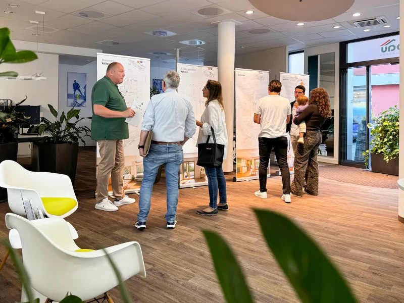 Beratungsgespräch vor den Plänen des Neubauprojekts Fessenbach im orbau Büro