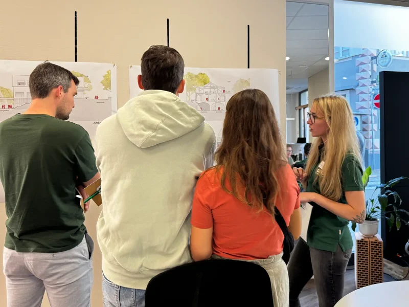 Mitarbeiterin der orbau Firmengruppe erklärt Projektpläne Gästen beim Pre-Sale Event