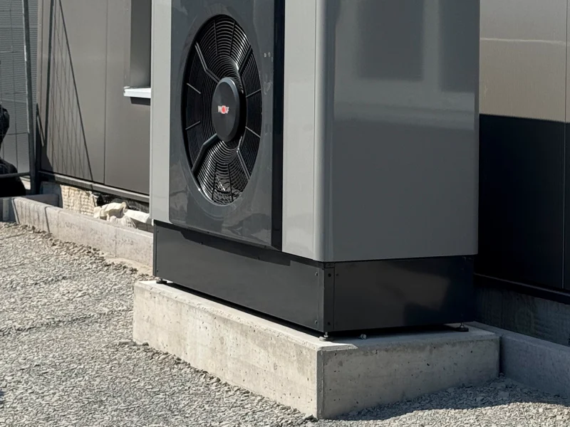 Nahaufnahme einer modernen Wärmepumpe an der Außenwand eines Industriegebäudes.